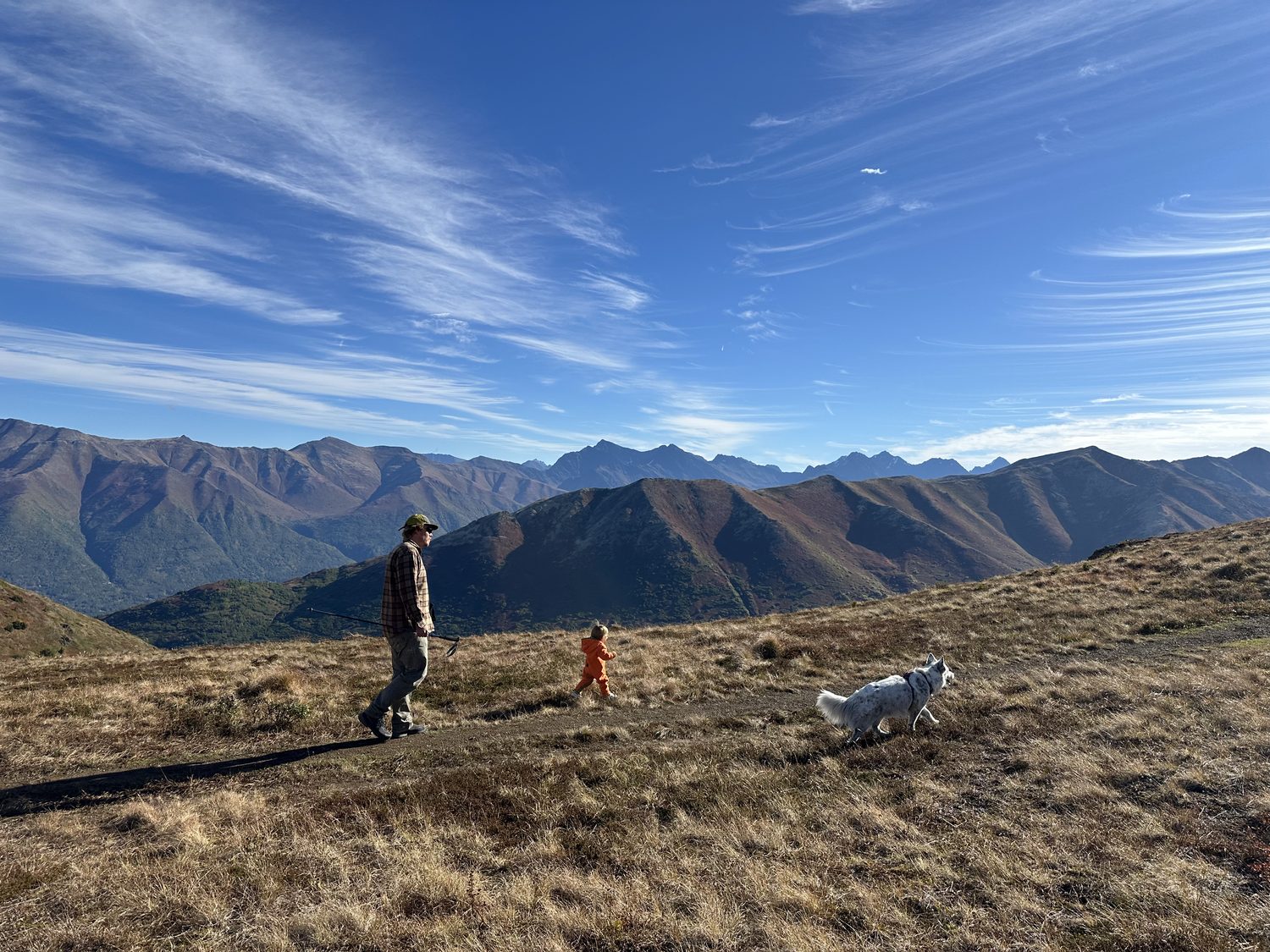 Walking a ridge trail in autumn with a small child and a dog, mountains beyond